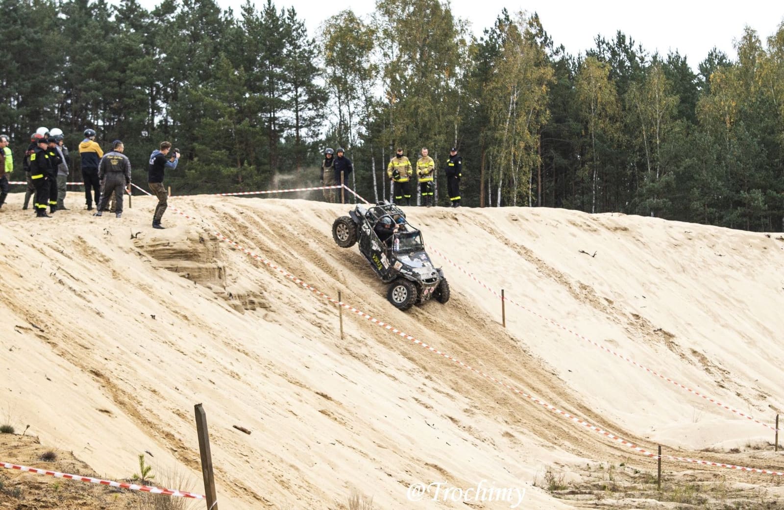 Buggy na stromym stoku z piachu, ludzie na górze