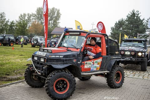 Kierowca w czerwono-czarnym buggy uśmiecha się na placu startowym