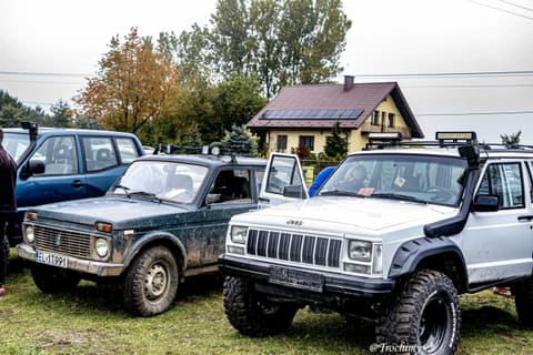 Łada Niva i biały Jeep Cherokee na parkingu uczestników