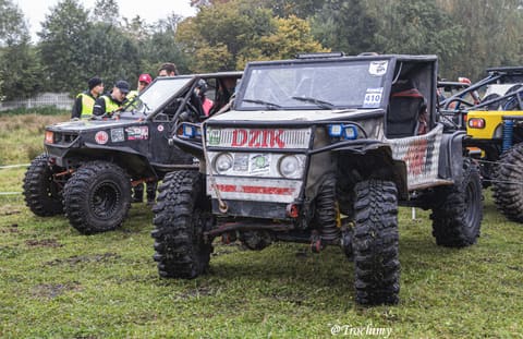 Czarne buggy z napisem Dzik w otoczeniu załóg na polu serwisowym