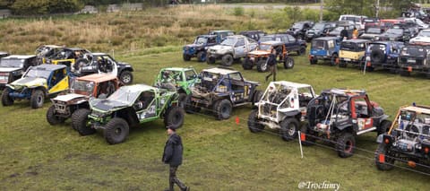 Widok z góry na rzędy buggy i terenówek na trawiastym parkingu