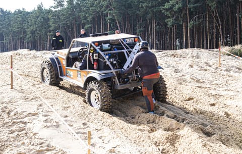 Pilot z podnośnikiem przy tyle buggy grzęznącego w głębokim białym piasku