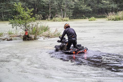Quadowiec klęczy na quadzie zanurzonym w zarośniętym stawie