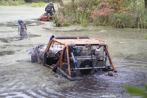 Buggy z pomarańczową klatką zanurzony w stawie, zawodnik ciągnie linę wyciągarki