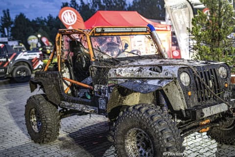 Terenowy Jeep z pomarańczową klatką i listwą LED w strefie bazy o zmierzchu