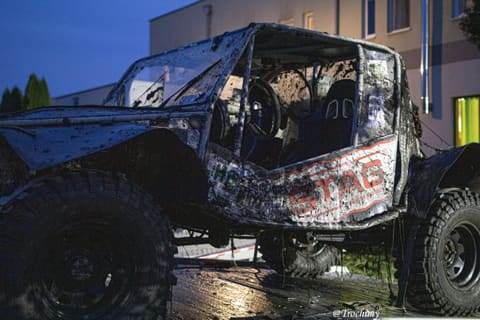 Zabłocony buggy z klatką bezpieczeństwa w świetle lamp na tle wieczornego nieba