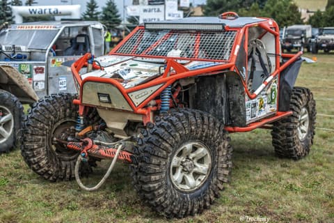 Pomarańczowy buggy z rurową klatką na dużych oponach w parku maszyn