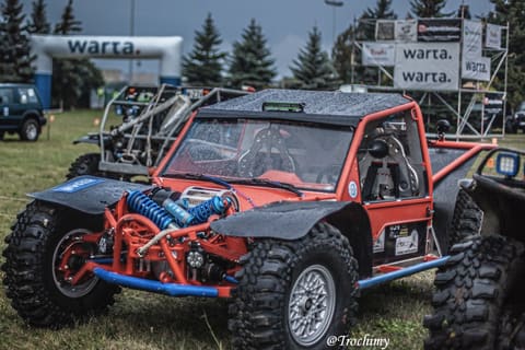 Pomarańczowy buggy z niebieskimi sprężynami zawieszenia w parku maszyn