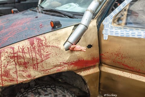 Detal złotej terenówki z imitacją krwi i sztuczną dłonią przy rurze