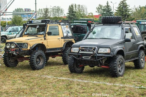 Żółte Suzuki Samurai i czarne Suzuki Vitara z orurowaniem w parku maszyn