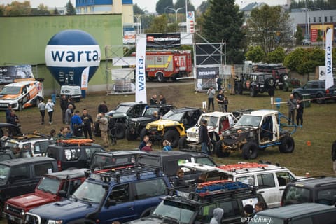 Park maszyn z góry, terenówki, uczestnicy i balon sponsora na trawiastym placu