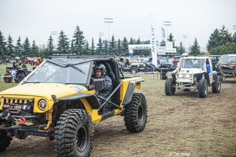 Żółty buggy z kierowcą w kasku przejeżdża przez trawiasty plac startowy
