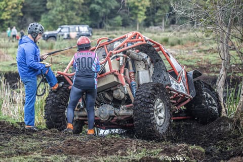 Załoga w kaskach przy pomarańczowym buggy z klatką, przygotowanie liny wyciągarki