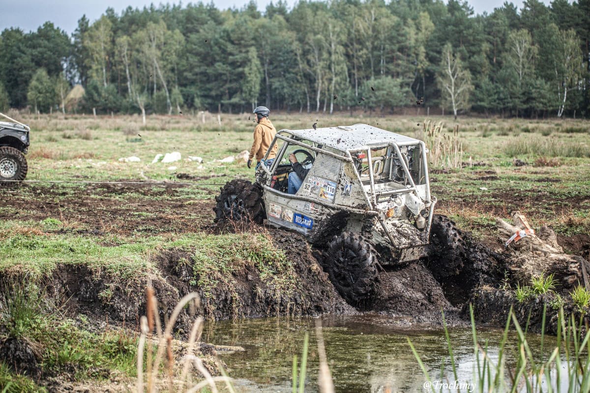 Buggy z klatką wspina się z rowu wypełnionego wodą na podmokłej łące