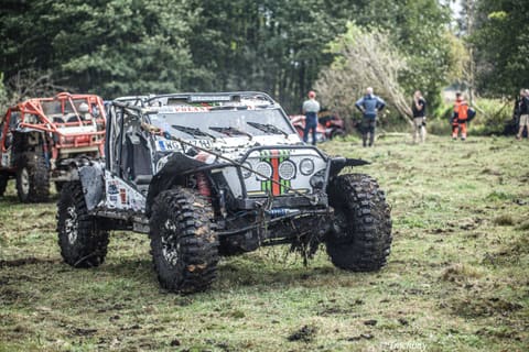 Srebrno-czarny buggy i pomarańczowy pojazd z klatką na trawiastej polanie
