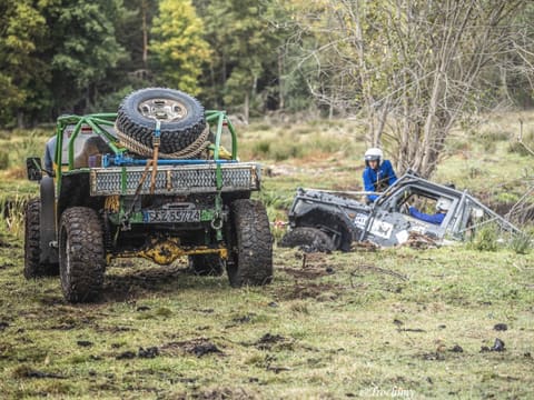 Zielona terenówka z kołem zapasowym wyciąga szary buggy z błotnistego rowu