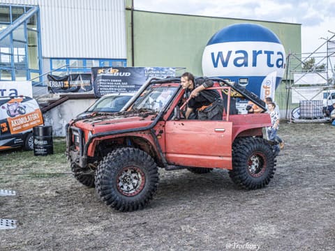 Czerwone Suzuki Samurai z klatką na placu bazy przy balonie sponsora