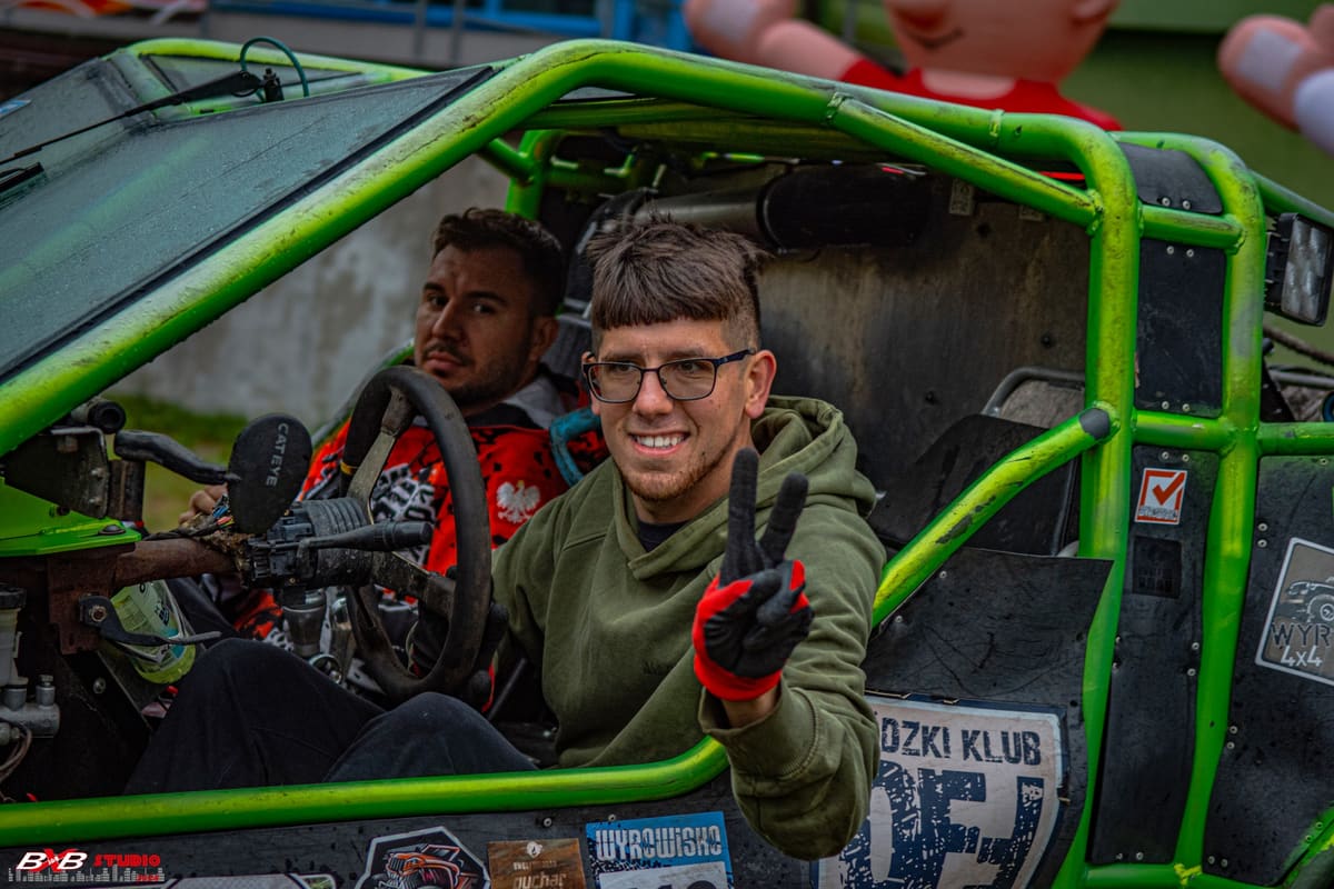 Uśmiechnięty pilot w okularach pokazuje znak pokoju z zielonego pojazdu z klatką