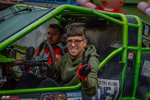 Uśmiechnięty pilot w okularach pokazuje znak pokoju z zielonego pojazdu z klatką