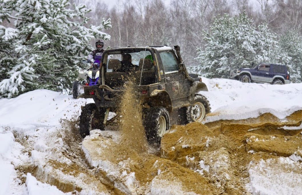 Suzuki Samurai bez dachu wyrzuca piasek na zaśnieżonym torze